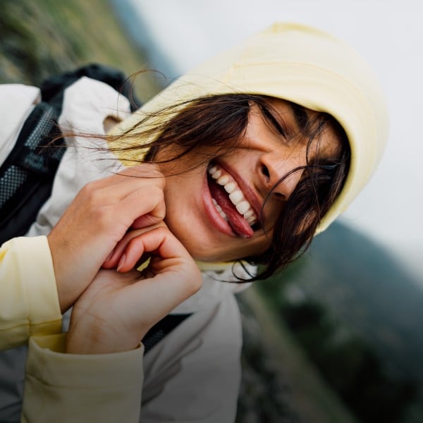 Frau und Mann in sommerlicher Outdoor-Kleidung klettern einen Felsen hinauf