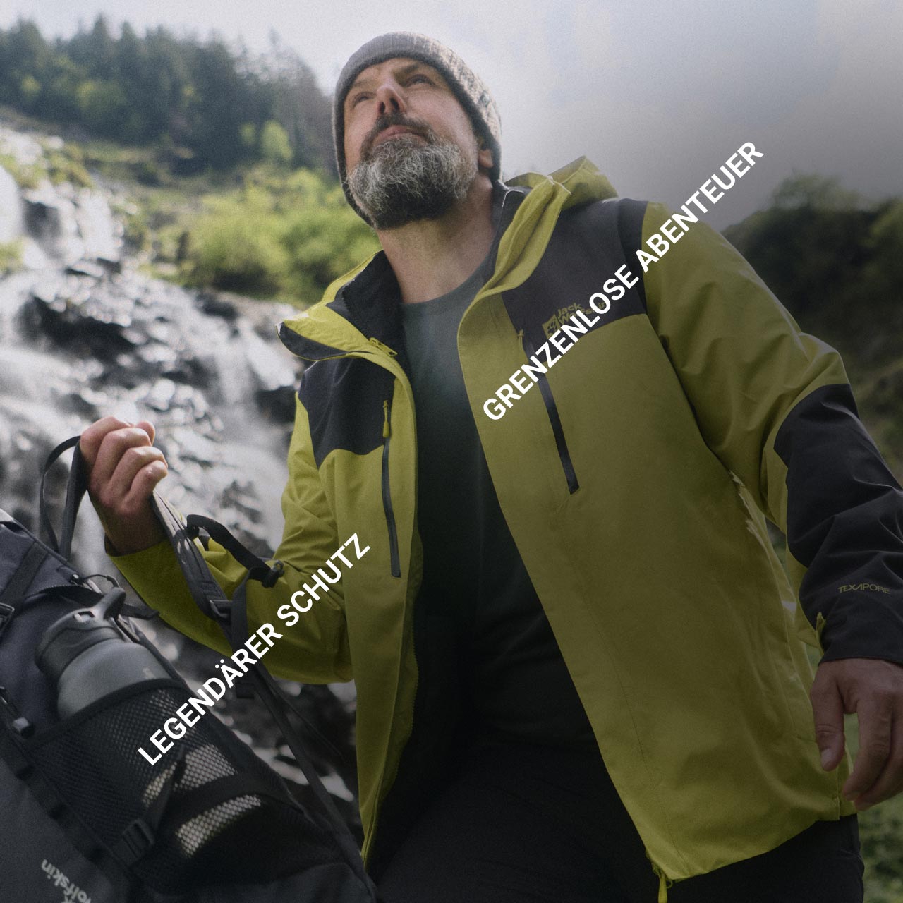 Ein Mann in gelber Jacke und beiger Mütze steht mit einem Rucksack im Freien und schaut nach oben. Der Text lautet „Legendärer Schutz“ und „Grenzenlose Abenteuer“