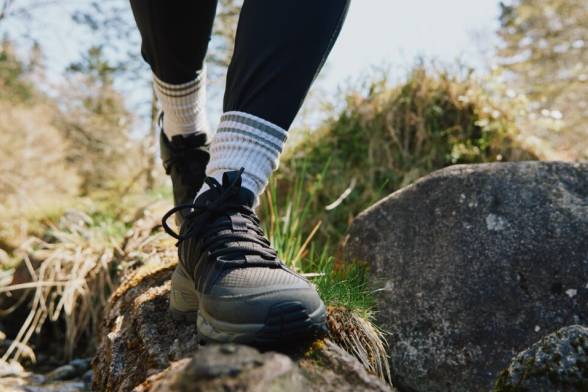 Nahaufnahme einer Person in Wanderschuhen beim&nbsp;Laufen über einen&nbsp;Felsstein