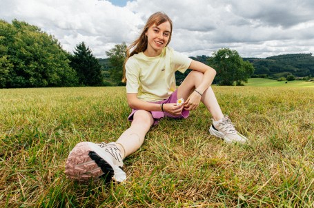Nahaufnahme von Beinen mit Wanderschuhen auf einem felsigen Weg.